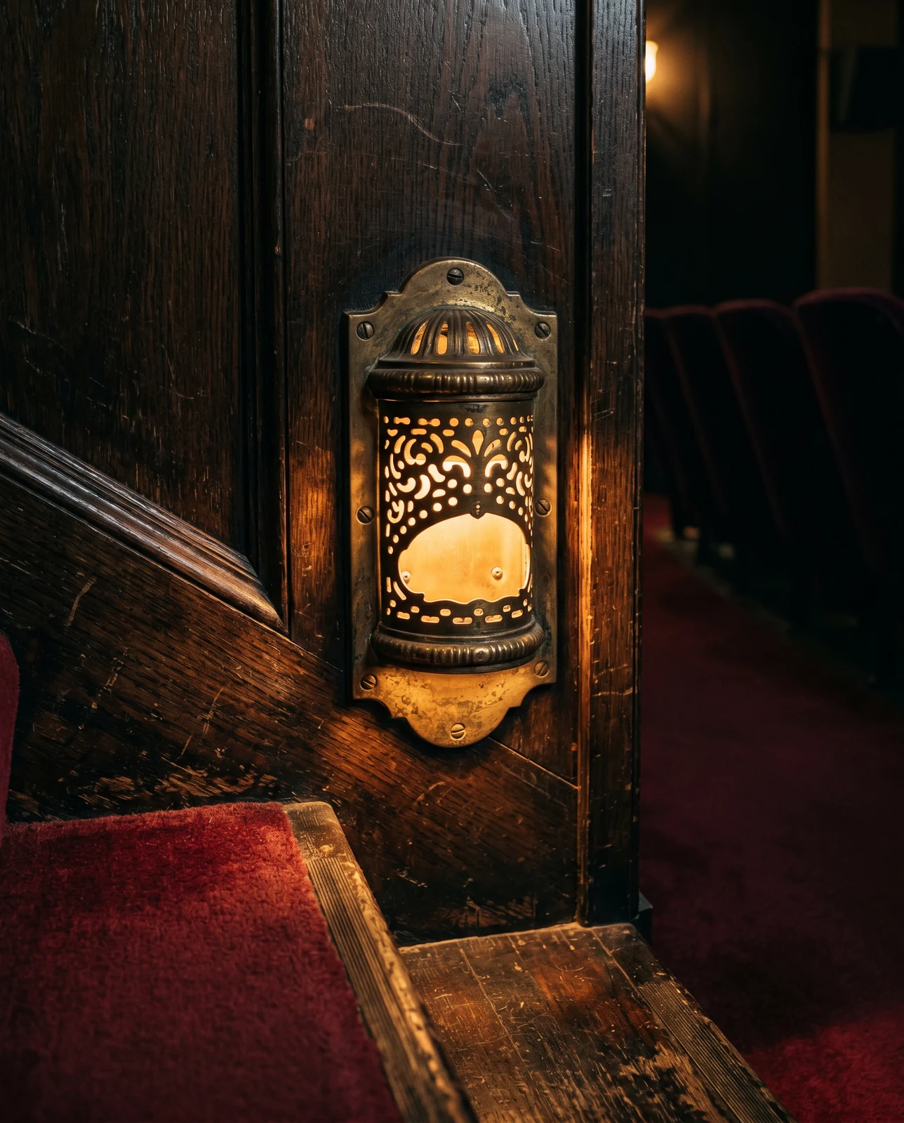 Heritage brass theater steplite glowing warmly on dark wood paneling