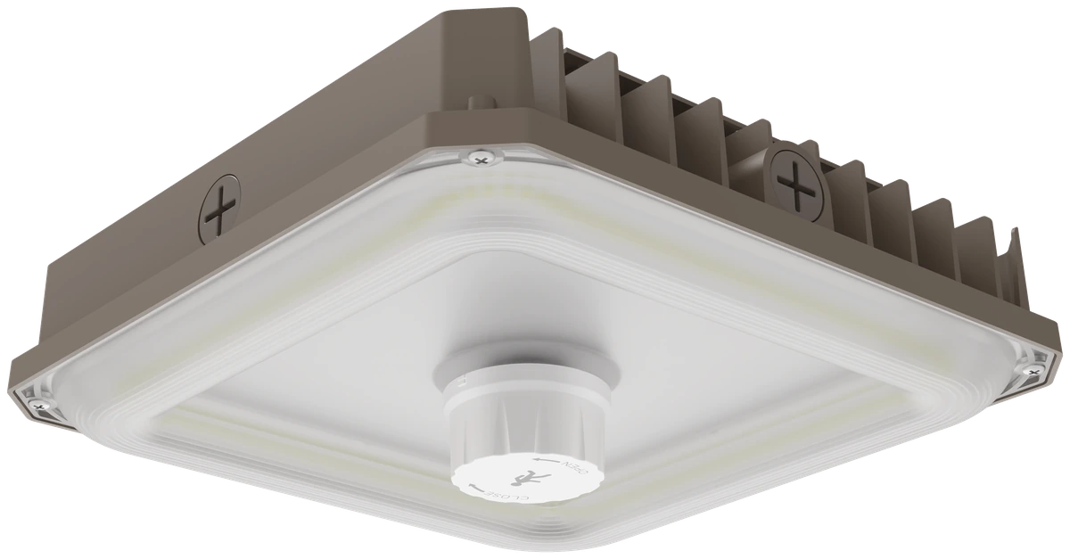 Navigator Series — 3/4 angle view of the LCNP3W canopy fixture with PIR sensor module visible at the center of the trim ring, dark bronze die-cast aluminum housing with channel-groove fins and twin Phillips-head mounting screws